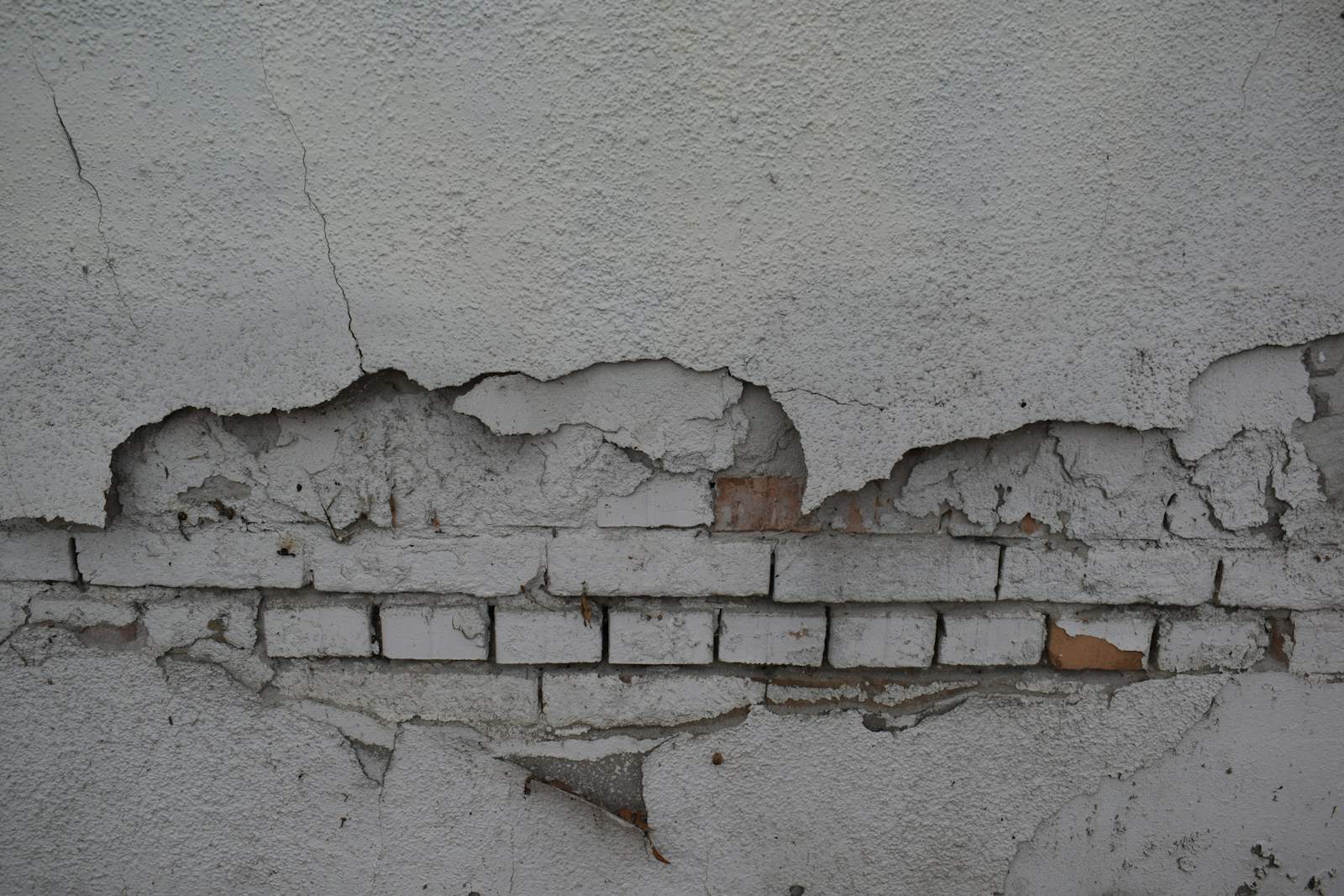 Pleisterlaag die van een bakstenen muur is afgebroken
